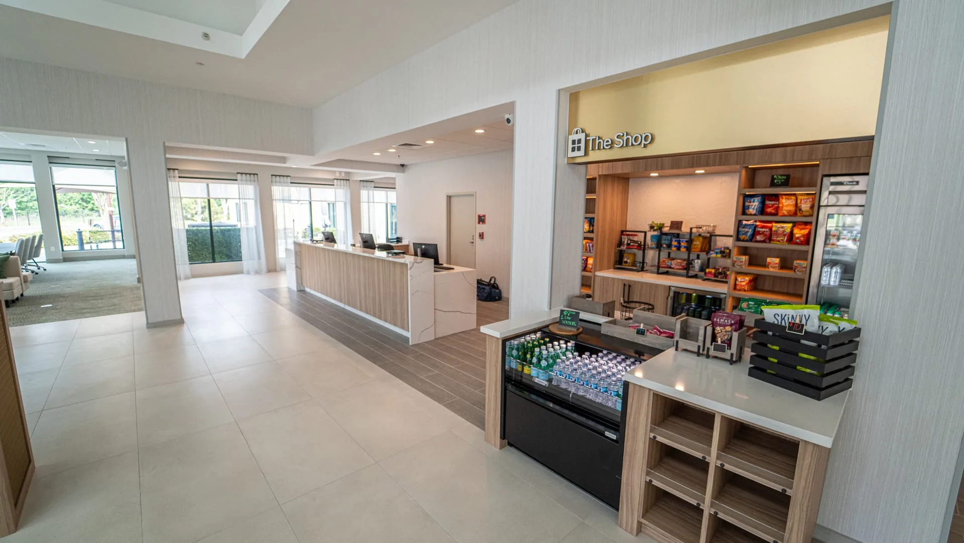 The Shop retail cabinetry with snack shelves, a drinks cooler and a light counter beside hotel reception